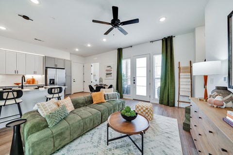a living room with a green couch and a ceiling fan
